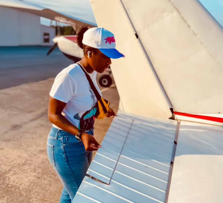 Person inspecting airplane wing on tarmac.