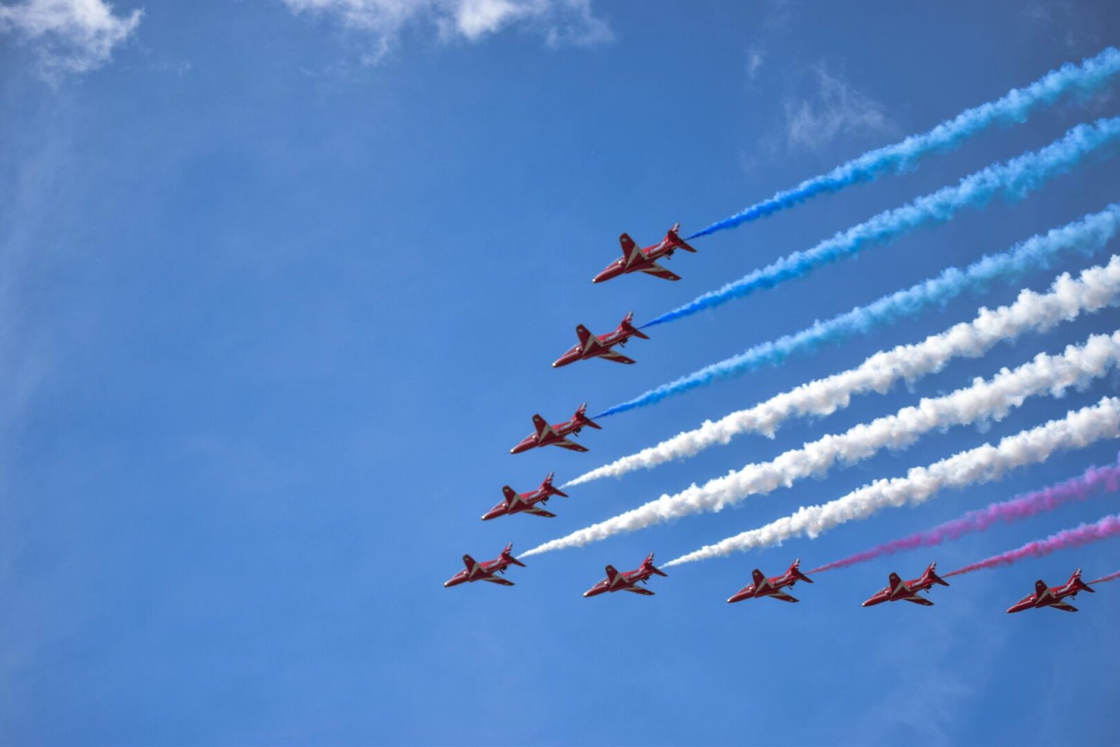 Airshow jets with colorful smoke trails.