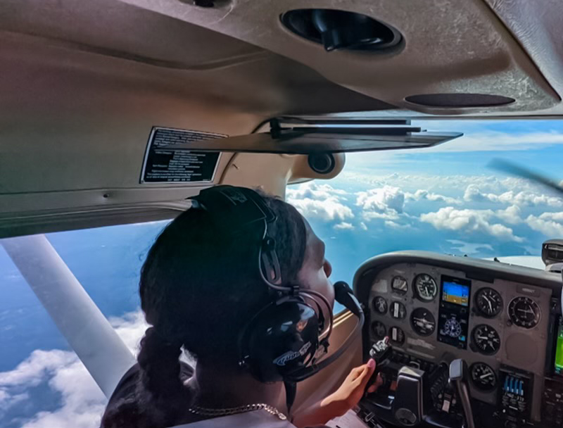 Pilot flying small aircraft above clouds.