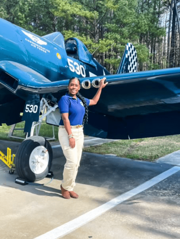 Person standing beside a vintage aircraft.