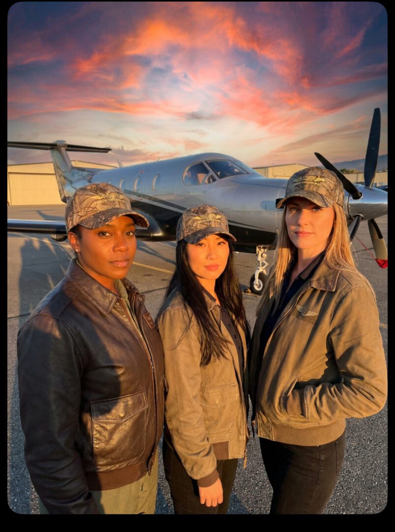 Three women in front of an airplane.