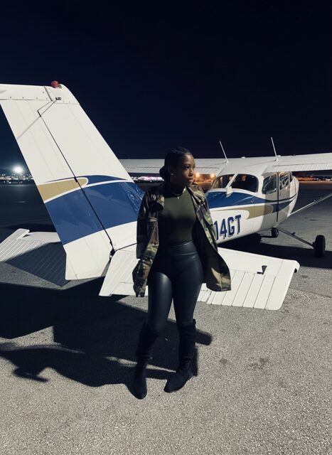 Person standing near a small airplane at night.