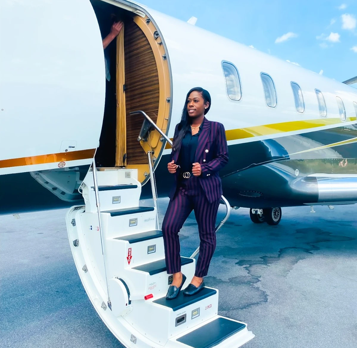 Woman exiting private jet on tarmac.